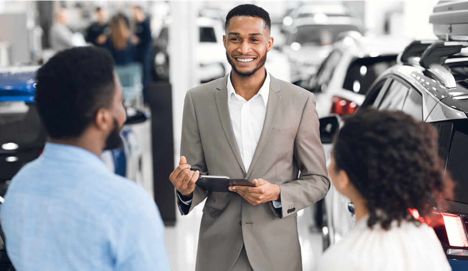 salesman-in-car-dealership-talking-with-customers--KNDGTRF-1
